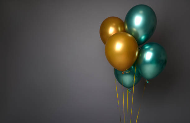 Beautiful pearly golden and green metallic inflated air balloons, isolated over gray background with copy space for advertising. Birthday, Anniversary, celebrations, Christmas and New Year concept stock photo