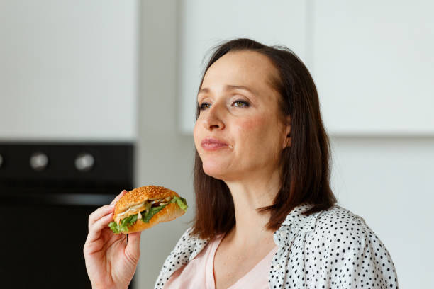 istock Brown haired pregnant lady eats burger without pleasure 1344431413