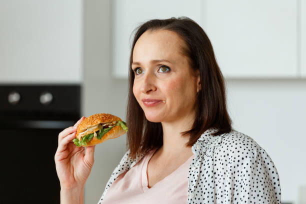 istock Brown haired pregnant lady eats burger without pleasure 1344431415