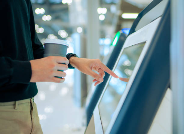 young asian man travelling by plane and doing self check in at the airport using a machine - self service stockfoto's en -beelden