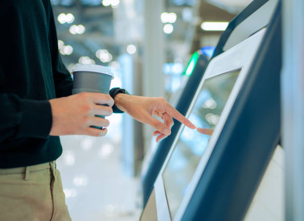 Young Asian man travelling by plane and doing self check in at the airport using a machine Young Asian man travelling by plane and doing self check in at the airport using a machine interactivity stock pictures, royalty-free photos & images