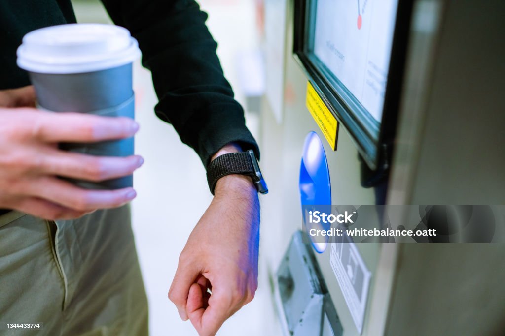 Close-up of an Asian man using contactless payment via a smart watch to pay for a ticket at a BTS station. Self Checkout Stock Photo