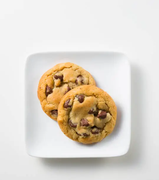 Two chocolate chip cookies on a white plate.