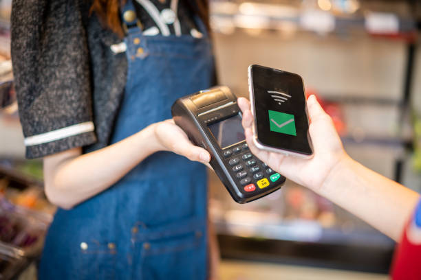 istock A woman uses her phone to make contactless payments 1344435558