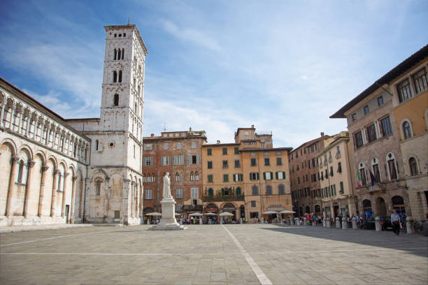 People sightseeing at the iconic Piazza dell'Anfiteatro, a public square in the walled center of Lucca, Tuscany, Italy. The ring of buildings surrounding the square follows the elliptical shape of the former second century Roman amphitheater of Lucca.