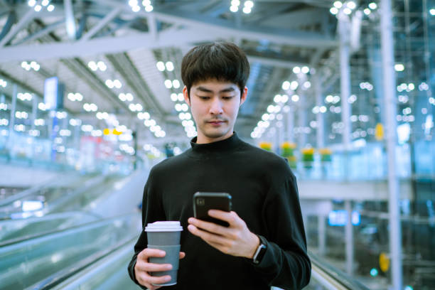 istock Businessman using phone on escalator at Airport 1344441364