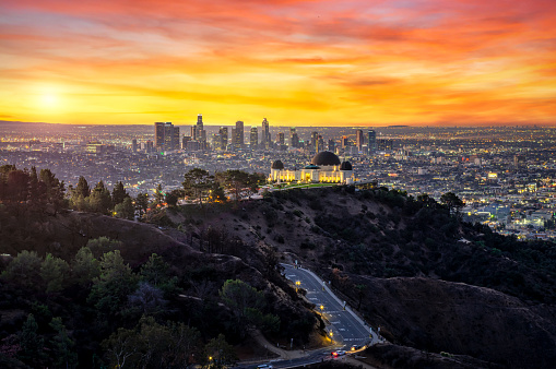Los Angeles Skyline at Sunrise with sun and dramatic sky and Griffith Park Observatory in the Foreground. California. USA