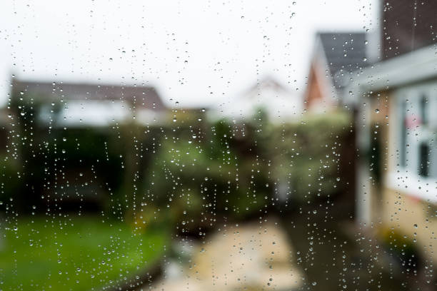 foco raso de gotículas de chuva vistas em uma janela de vidro duplo conservatório olhando para uma área de pátio. - raining cats and dogs - fotografias e filmes do acervo