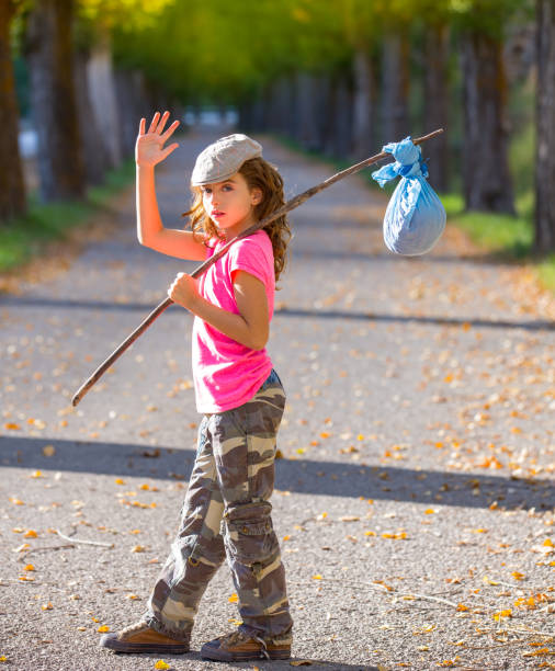 istock little kid with hobo stick bag and bundle girl saying goodbye 1344445445
