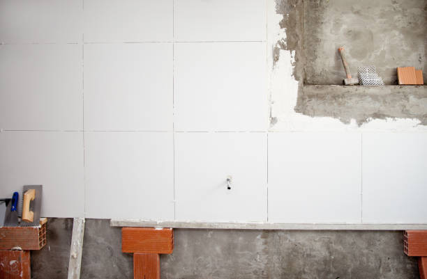 istock tiles white wall contruction with trowels tools 1344446313