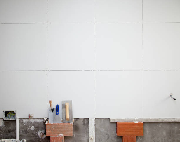 istock tiles white wall contruction with trowels tools 1344446335