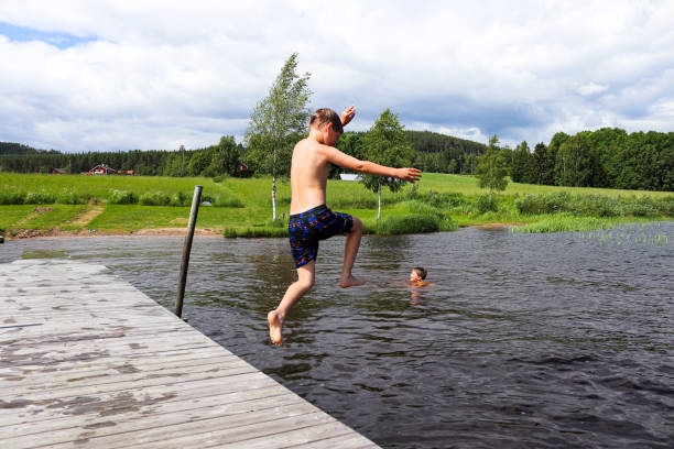 istock Boy jumping into the water from jetty 1344446522