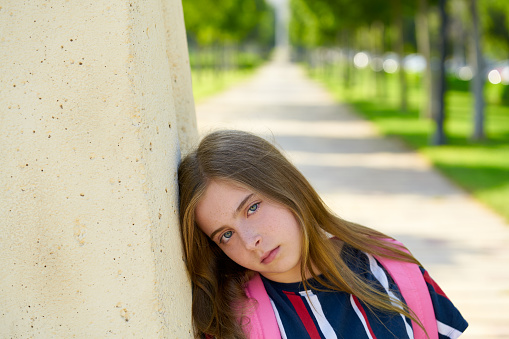 Blond kid student girl sand bored face gesture in the park