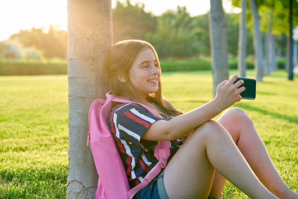 istock Blond student kid girl with smartphone in park 1344447532