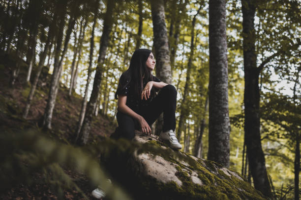 istock Teenager resting on rock while enjoying a hike in the green beech forest. 1344447750