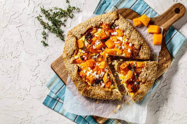 pumpkin galette with caramelized onion, cream cheese, thyme and crumbled feta cheese on a wood board on a white textured table, flat lay, free space - butternut squash roasted squash cooked imagens e fotografias de stock