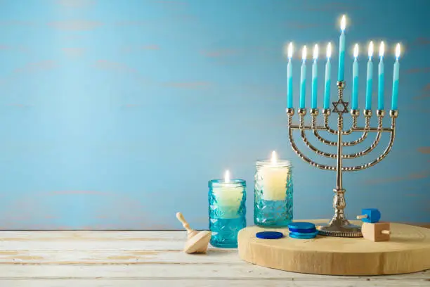 Jewish holiday Hanukkah concept with menorah, candles and dreidel on wooden table. Background for greeting card or banner