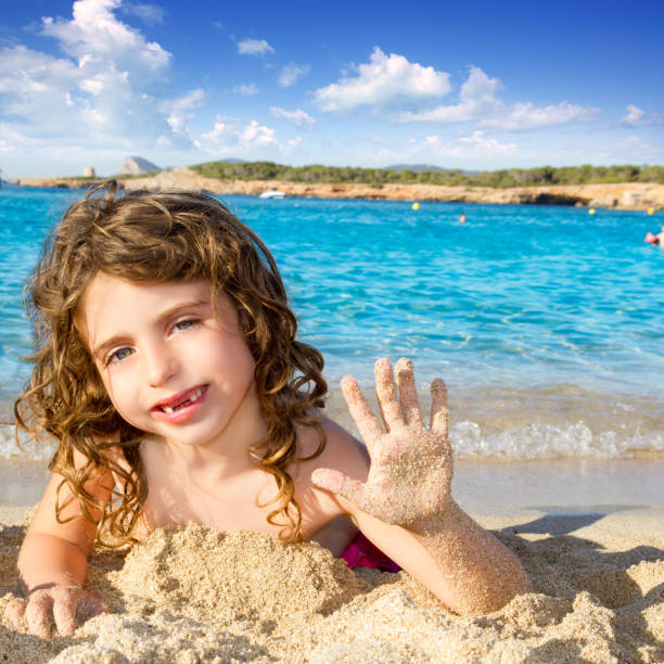 istock Little girl greeting hand gesture in sandy beach 1344451350