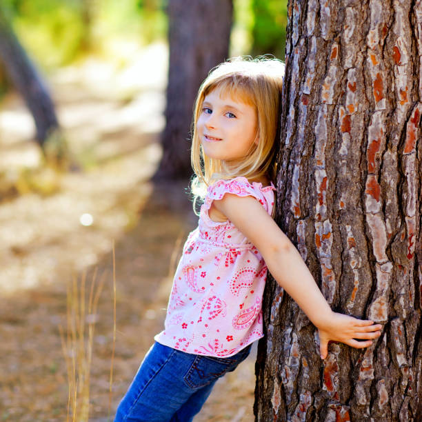 istock blond kid girl on autumn tree trunk 1344451712