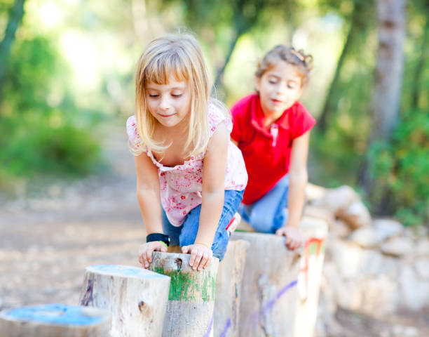 istock kid girls playing on trunks in forest nature 1344452472