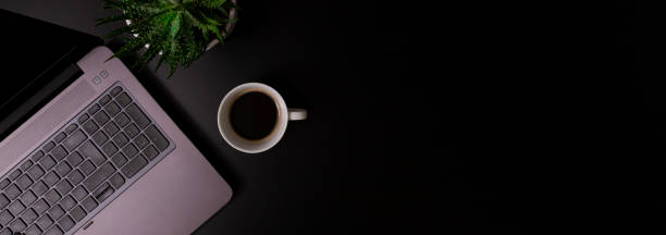 istock Copy space office black table with laptop, notebook, pencil and coffee cup with plat. 1344454860