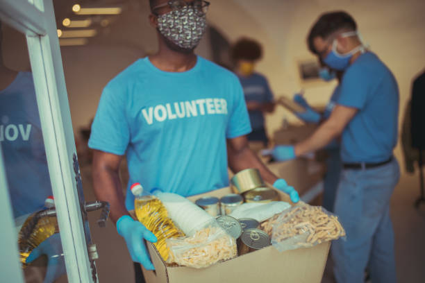 Time well spent in practicing generosity Depicting a scene at the volunteering center where a group of people is helping the society by filling up the boxes with food and home supplies. altruism stock pictures, royalty-free photos & images