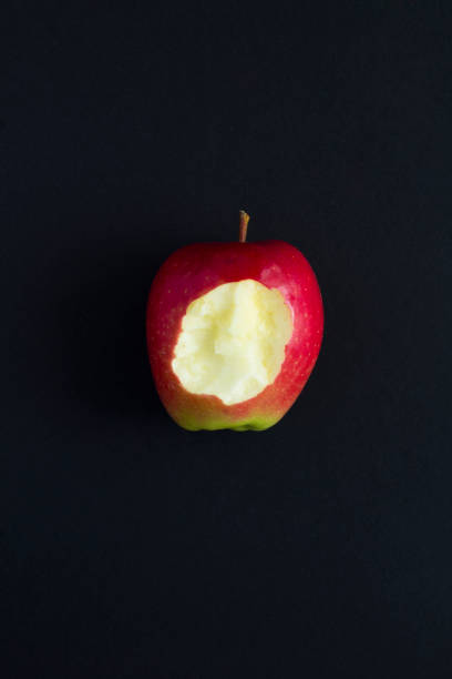 Top view of bitten apple on a black background. Copy space. Natural food. Top view of bitten apple on a black background. Copy space. Natural food. apple bite stock pictures, royalty-free photos & images
