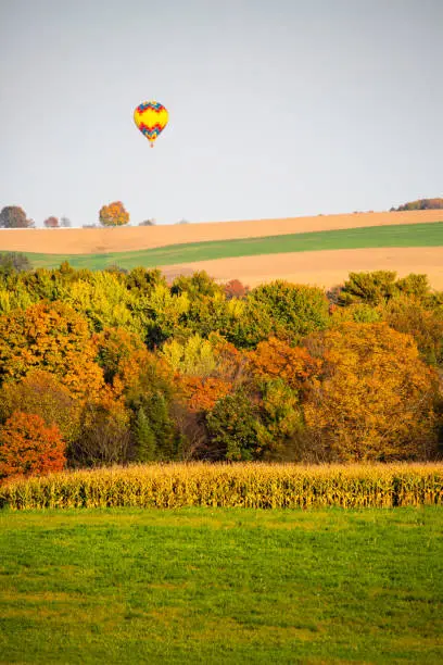 Hot air balloon flying over Wisconsin farmland in late September, vertical