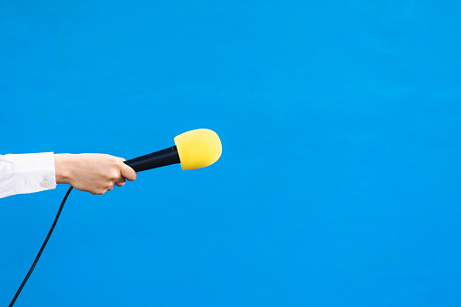 manos de una mujer sosteniendo un micrófono amarillo con espacio de copia, concepto de entrevista. photo