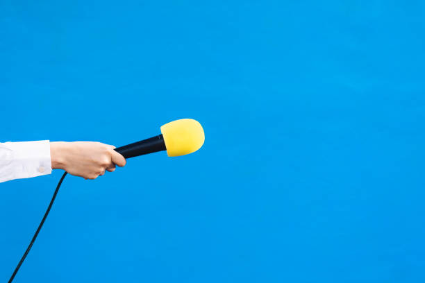 manos de una mujer sosteniendo un micrófono amarillo con espacio de copia, concepto de entrevista. - journalism fotografías e imágenes de stock