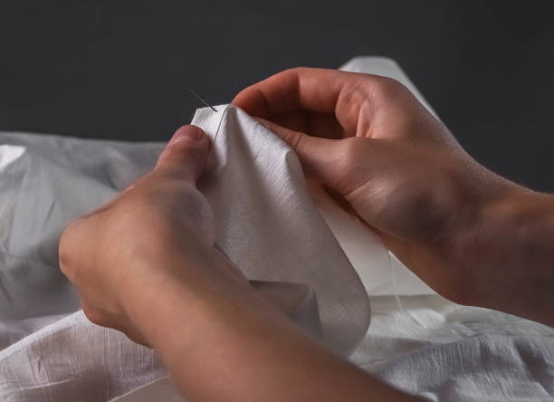 istock Manual sewing. Hands with needle and white cotton cloth 1344458492