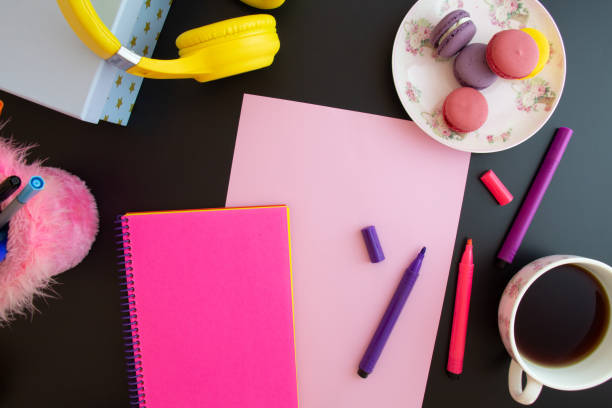 istock paper, notebook, colored pencils, macarons on a black background 1344459434