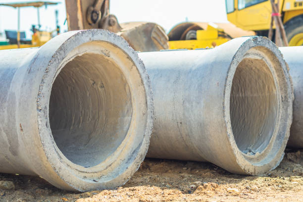 istock Stack of concrete drainage pipes for wells water discharges laying an external sewage system at a construction site outdoors warehouse. Civil infrastructure, industry manufacturing of cement products 1344459520