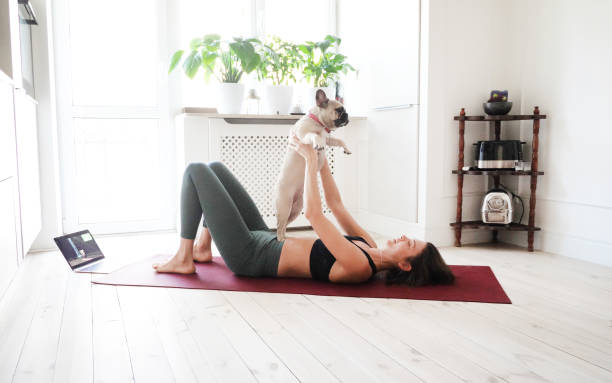 istock Young woman doing exercises at home with her dog 1344464919