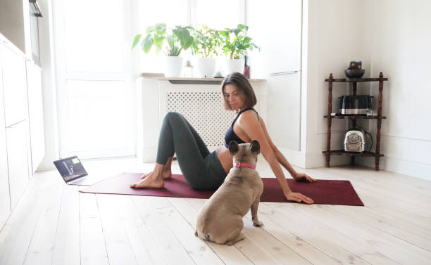 istock Young woman doing exercises at home with her dog 1344464922