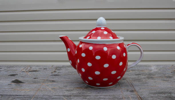 istock Red vintage teapot with polka dot pattern on wooden background 1344473141