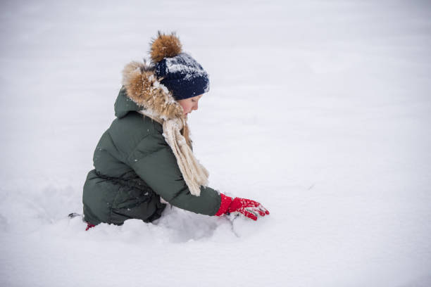 istock Girl makes a snowman outside in winter time 1344476946