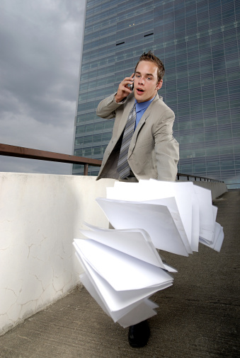 Bad day - fumbler businessman with mobile phone in front of modern business building.