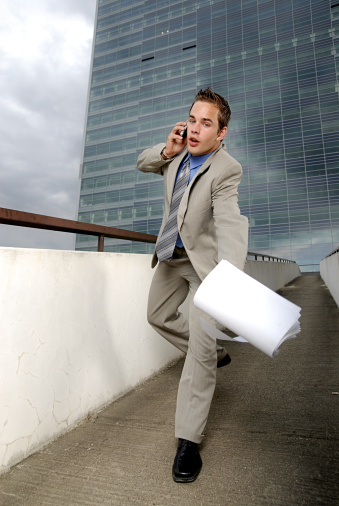 Bad day - fumbler businessman with mobile phone in front of modern business building.