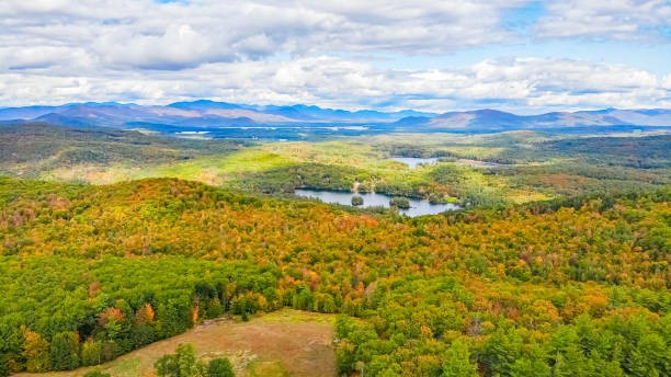 nuvens refletindo sobre a região de mountan de new hampshire com cores de outono começando - autumn falling leaf new england - fotografias e filmes do acervo