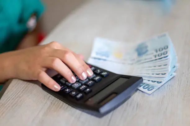 Photo of Female hands doing calculations on table with calculator and turkish liras