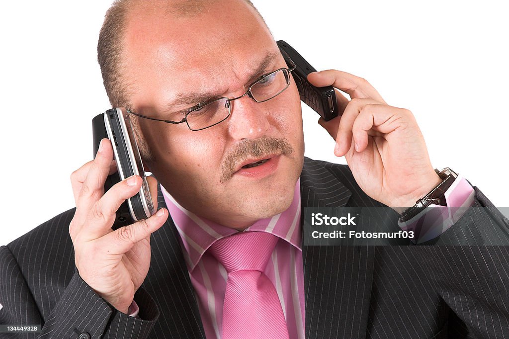 Mobile unit Businessman talking on three phones at the same time clearly looking a bit agitated Adult Stock Photo