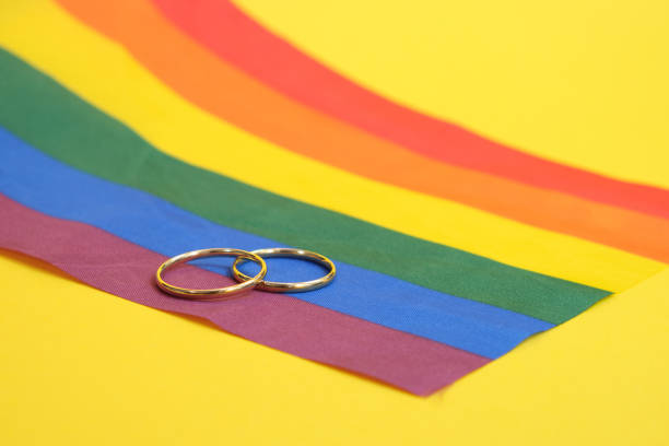 istock wedding rings on lgbt flag, yellow background, copy space 1344494952