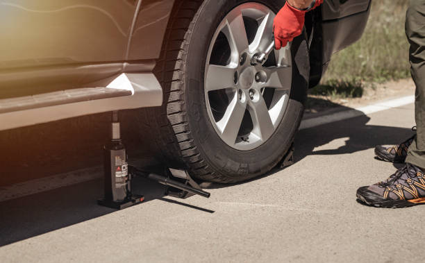 istock Hydraulic car jack is put under auto by hands in gloves, close up 1344497705