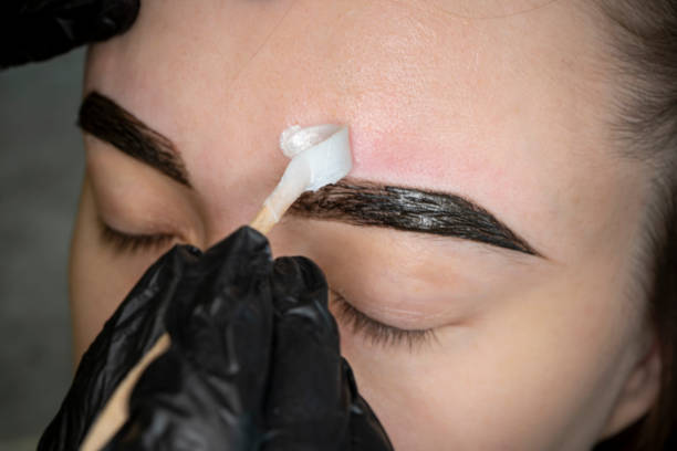 Removing eyebrows with hot wax. Brow master applying hot wax for brows epilation, lamination and waxing. Professional care for face and brow beauty procedures.