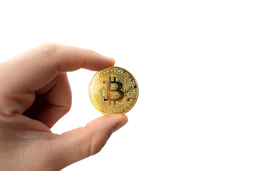 Diyarbakir, Turkey - September 25, 2021: Close up shot of a golden Bitcoin coins on hand holding bitcoin coin image with white background
