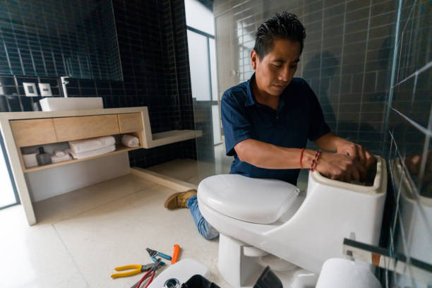 lateinamerikanischer klempner repariert eine toilette im badezimmer - klempner fotos stock-fotos und bilder