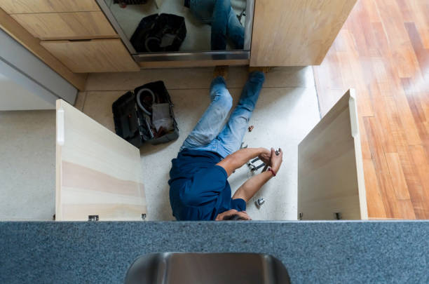 Plumber fixing a broken pipe in the kitchen Plumber lying on the floor under the sink fixing a broken pipe in the kitchen - essential services concepts property damage stock pictures, royalty-free photos & images