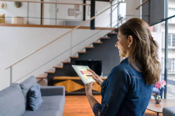 Adult Latin American woman controlling the ambiance of her house using a home automation system on her tablet - smart home concepts