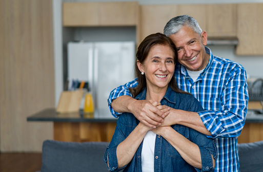 Portrait of a loving adult Latin American couple smiling at home and looking at the camera - lifestyle concepts